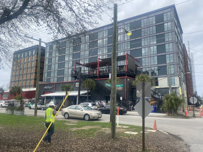 Completed mixed-use building with red steel balconies above ground-floor storefronts