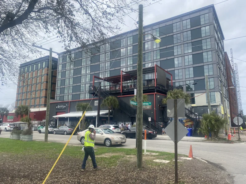 Crew member working the verge in front of a finished six-storey mixed-use facade