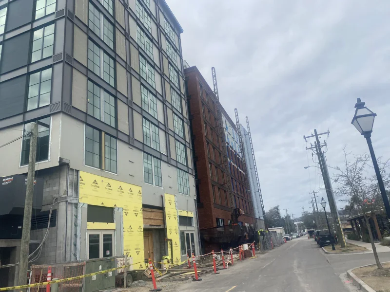 Mixed-use block under construction, painted panels above sheathing still exposed at street level