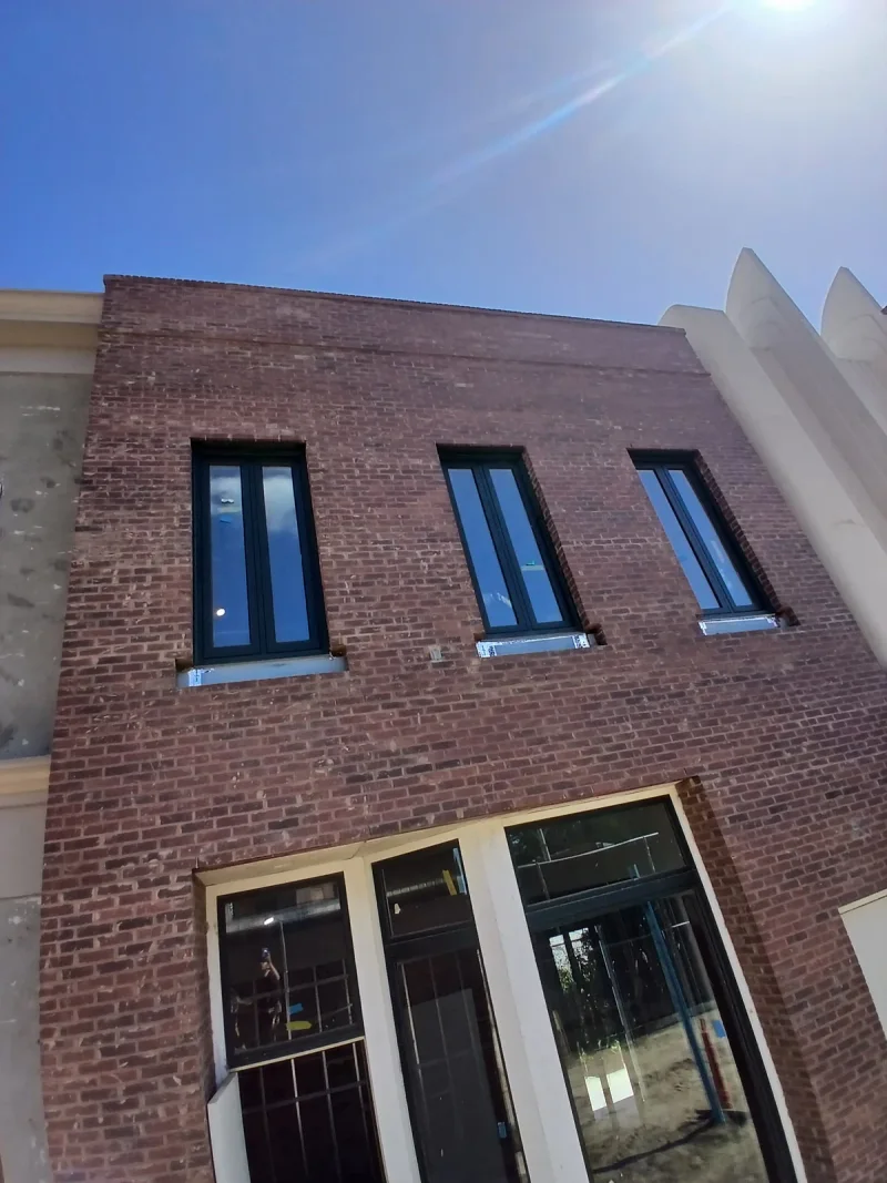 Restored brick facade with new black-framed windows and painted stone banding