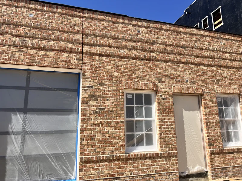 Brick garage elevation with the door and roll-up opening masked off ahead of painting