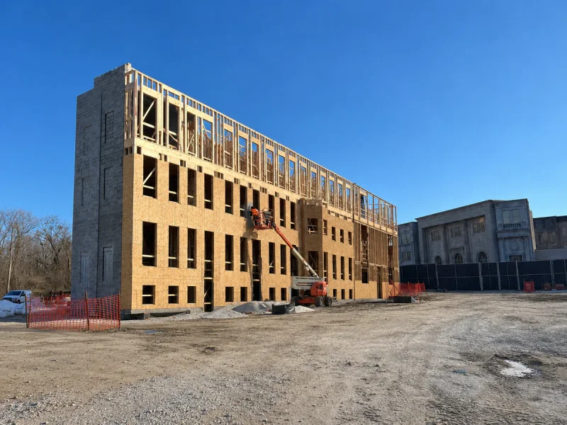 Three-storey building at framing stage, timber structure and bare sheathing open to the street