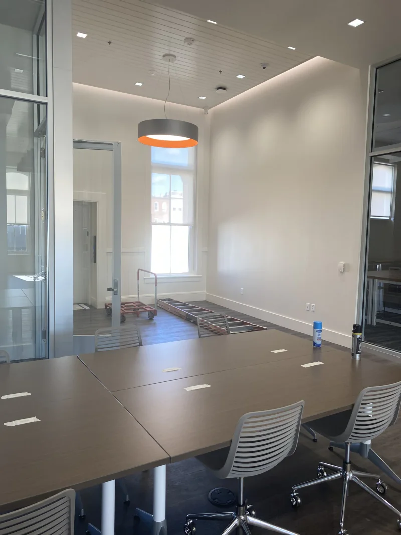 Conference room finished in soft white with a beadboard ceiling and a copper pendant light
