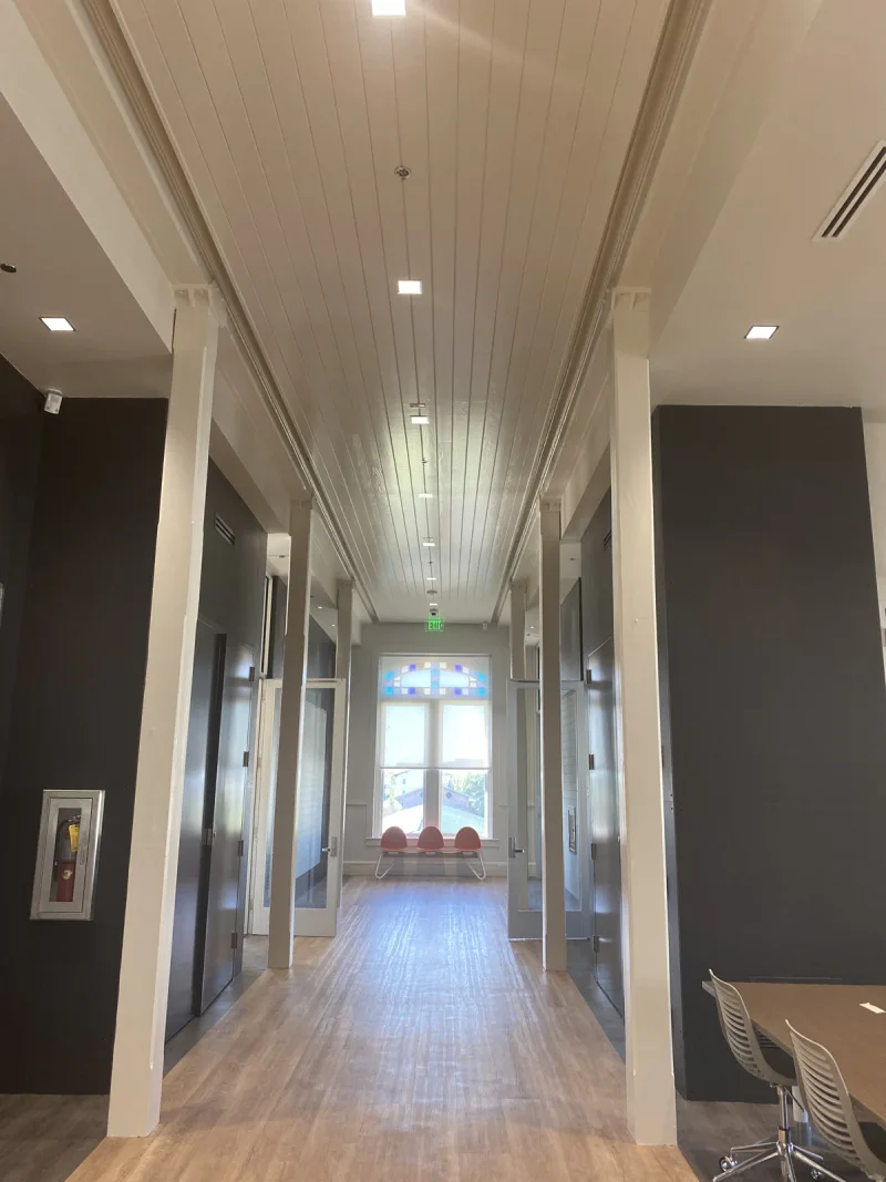 Finished corridor framed by painted columns, with a white beadboard ceiling above dark walls