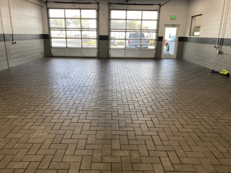 Cleaned herringbone paver floor with white block walls and a grey painted band above