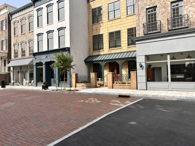 Completed storefronts with painted awnings and trim along a finished paver street