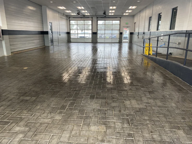 Wide view of a freshly washed paver floor reflecting the overhead lights in a service bay