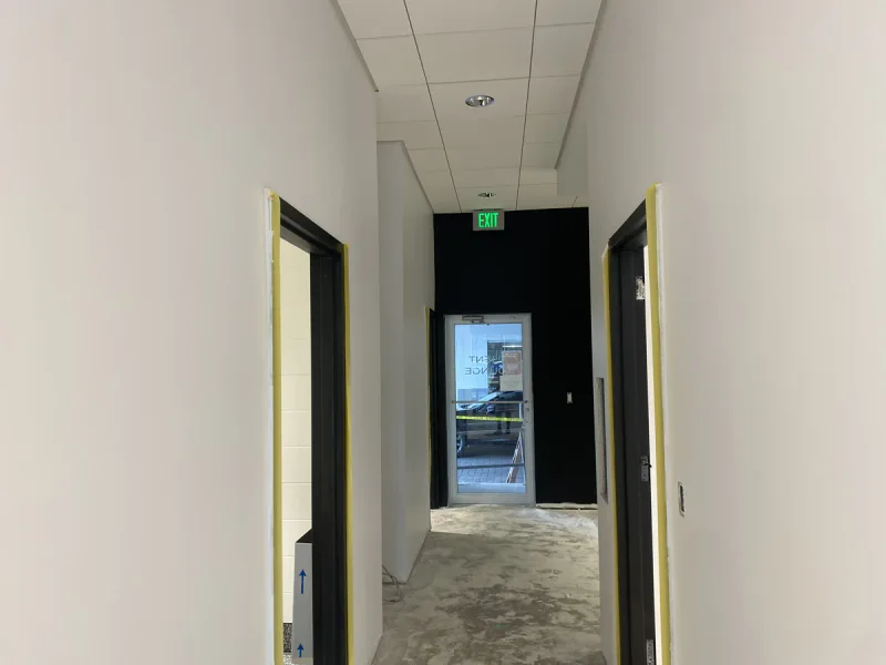 Newly painted corridor with masked door frames leading to a black accent wall