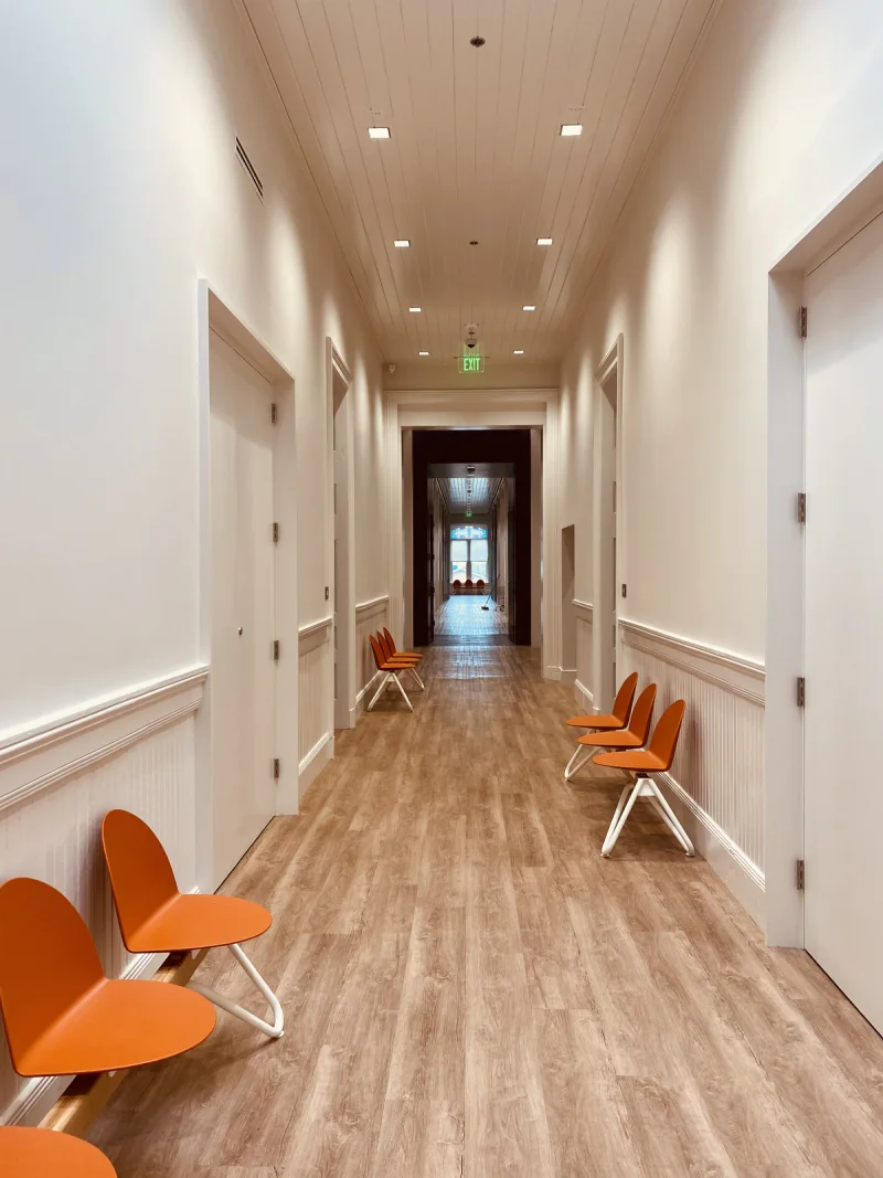 Bright hallway with white wainscot panelling, orange seating and new plank flooring