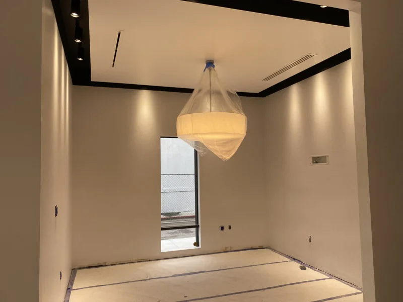 Small room finished in warm white with a black ceiling reveal and a fabric pendant light