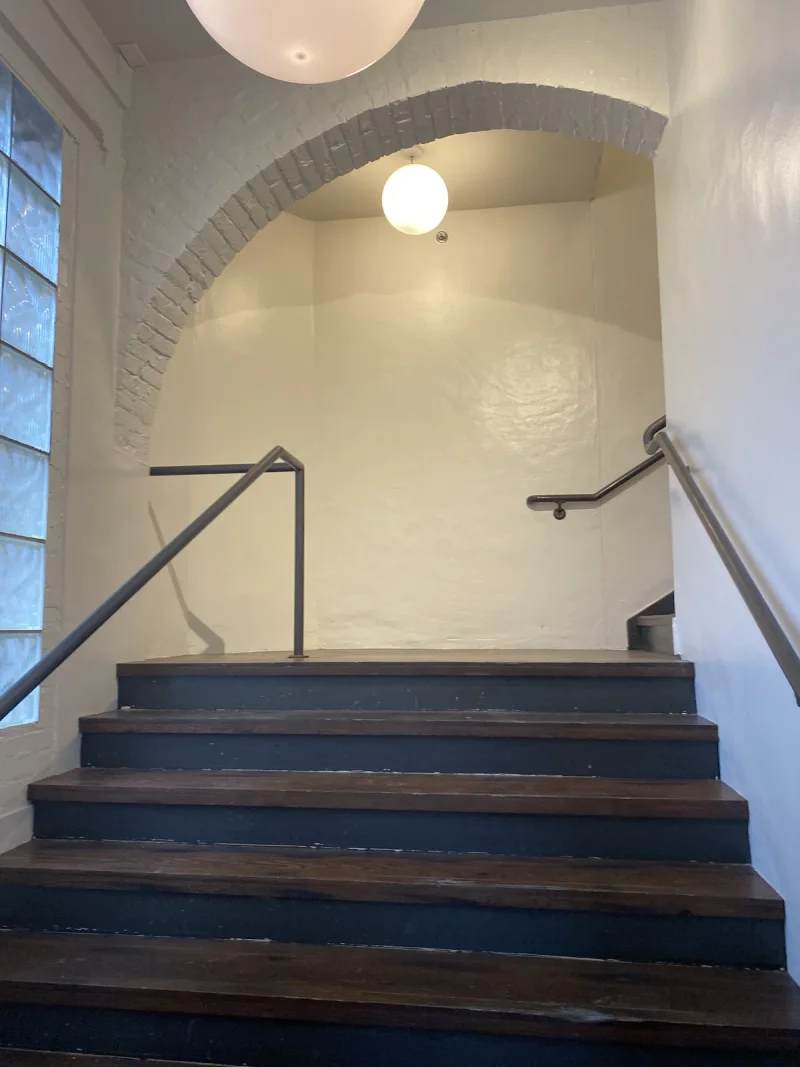 Stairwell landing with a whitewashed brick arch above navy-painted treads